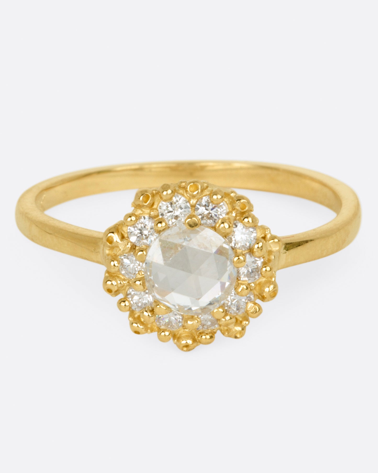 A rose cut round diamond ring with a halo of smaller round brilliant cut diamonds.