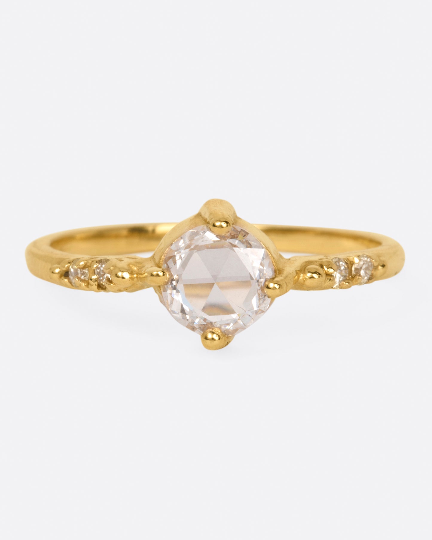 A yellow gold ring with a prong set rose cut diamond at the center and two diamonds on either side, shown from the front.