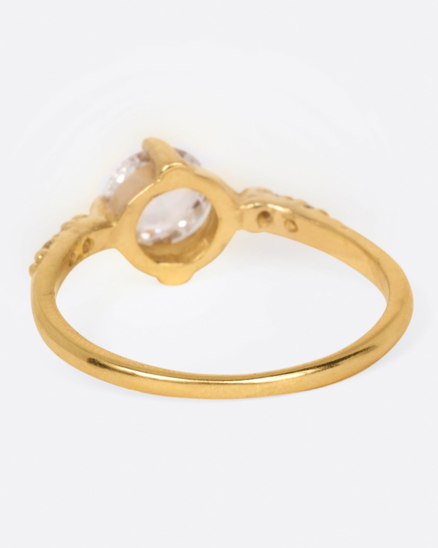A yellow gold ring with a prong set rose cut diamond at the center and two diamonds on either side, shown from the back.