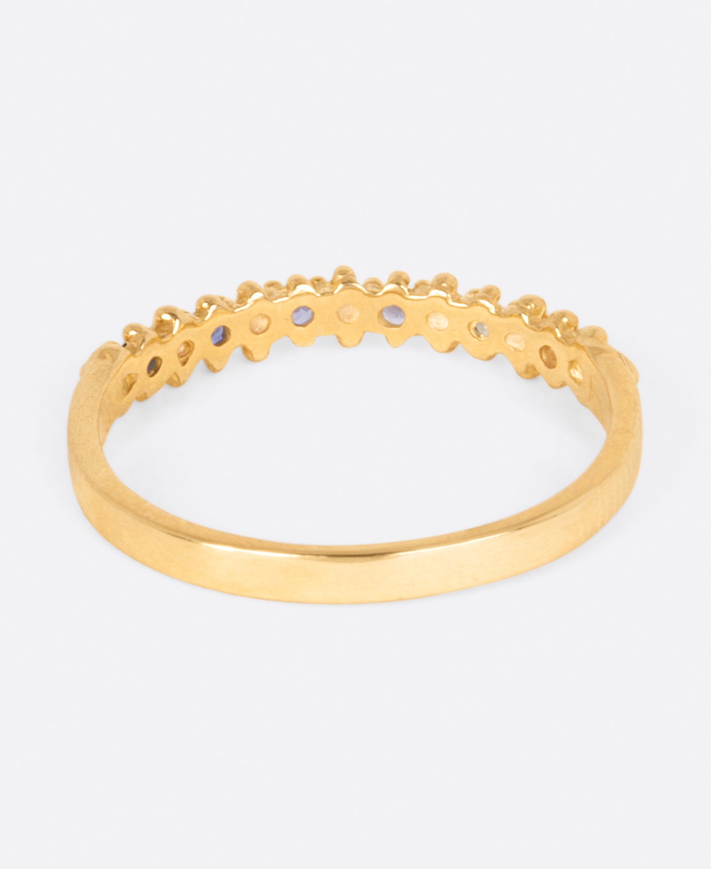 A textured yellow gold band with six sapphires in ombré order from white to dark blue, shown from the back.