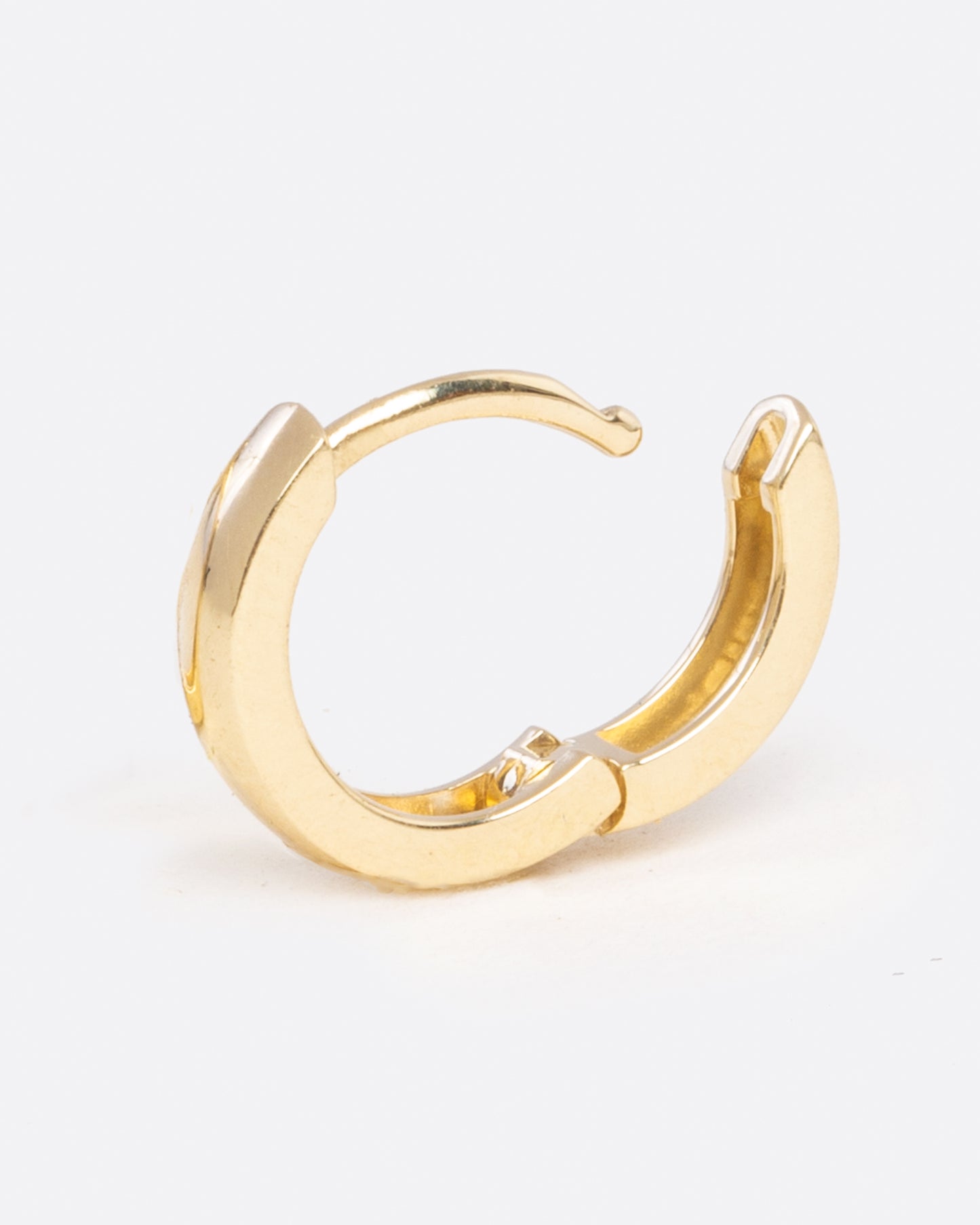 a tiny yellow gold hoop earring with a hinge in the middle, shown open