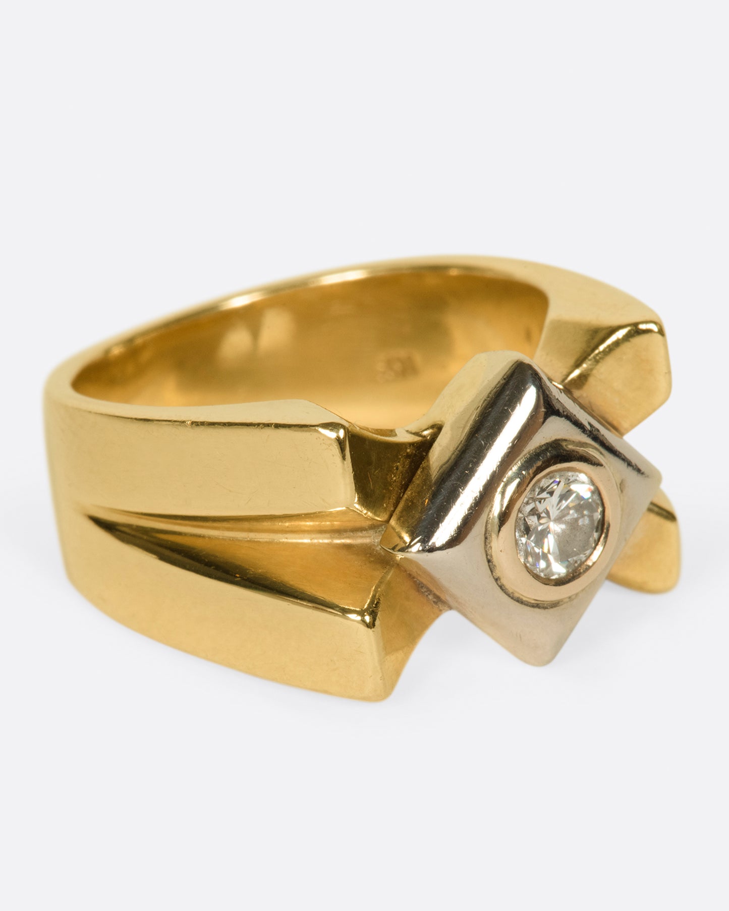 A heavy, gold, X-shaped ring with a white gold square and a round diamond at its center.