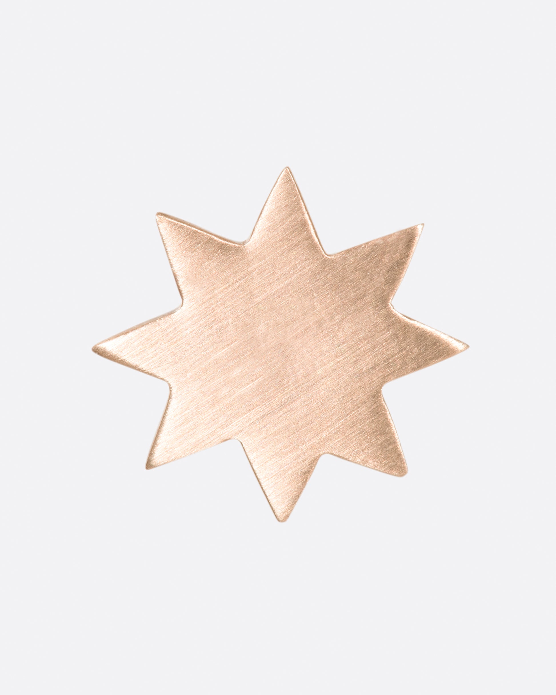 A brushed metal, pale pink eight-point star earring.