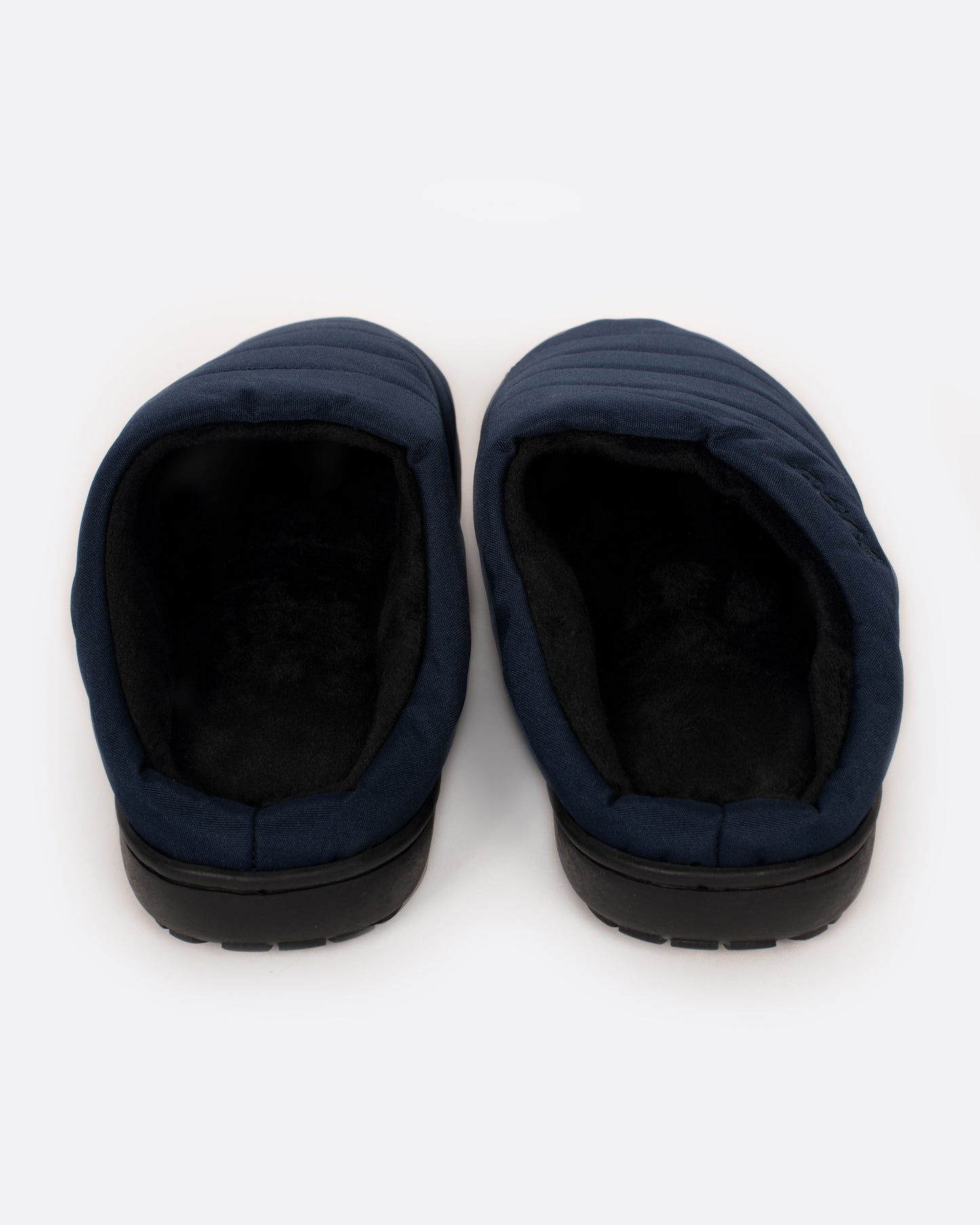 A pair of navy nylon slippers with black rubber soles, shown from the back.