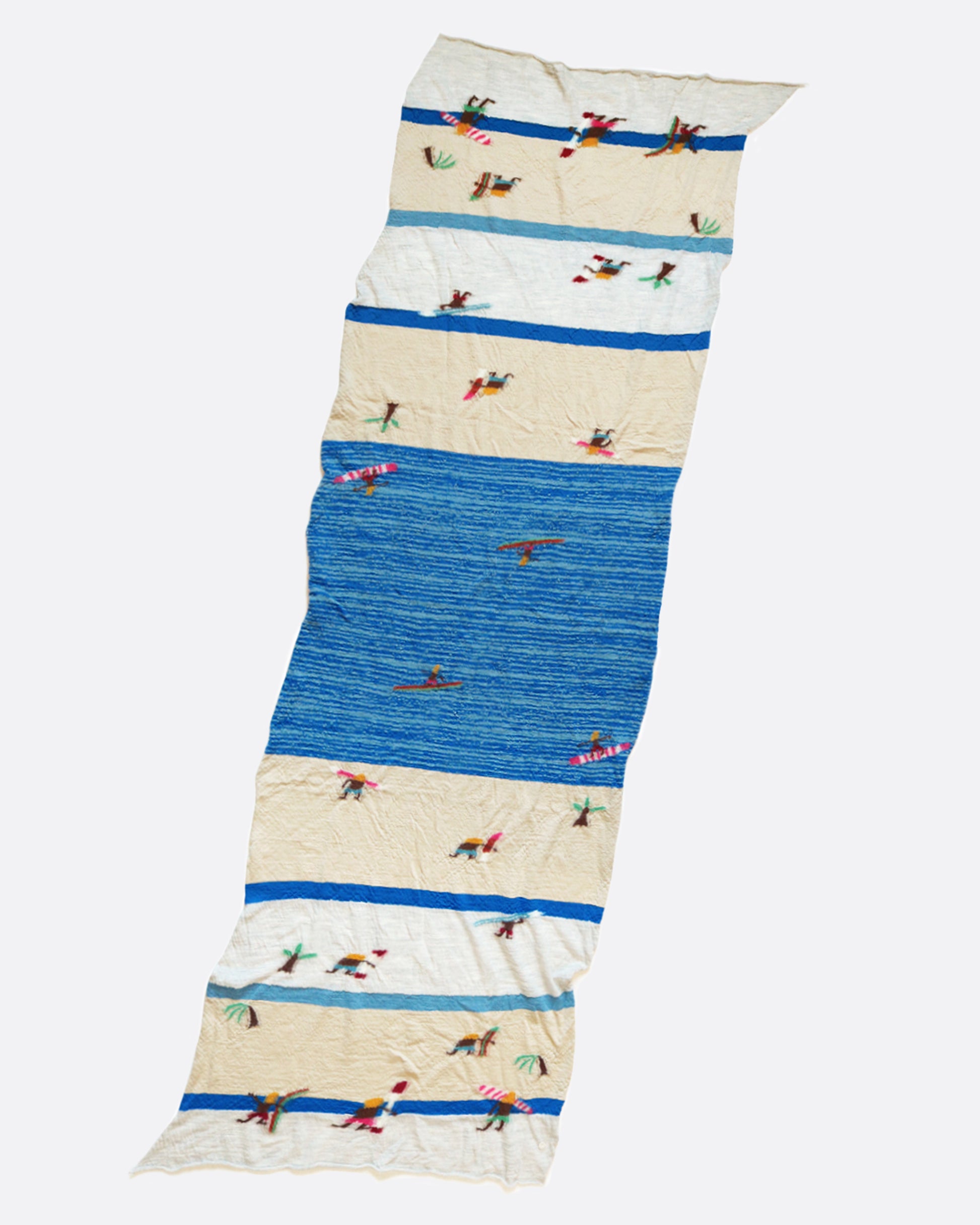 A compressed wool scarf with a fun pattern of surfers on a sandy beach.