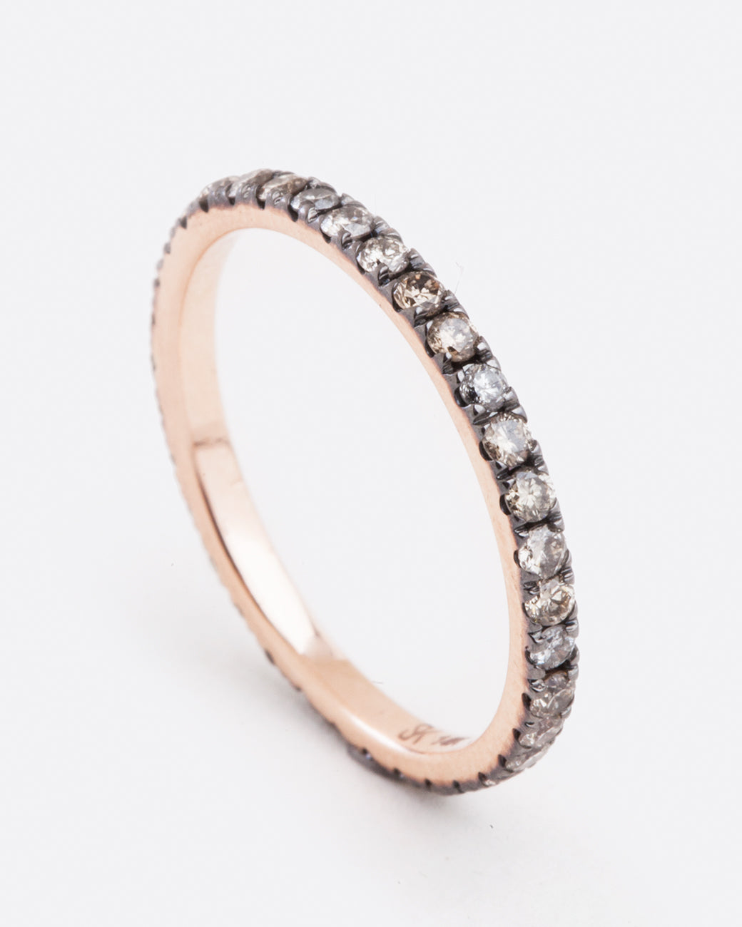 angled side view of a rose gold eternity band from designer selin kent featuring champagne and grey diamonds in varying shades