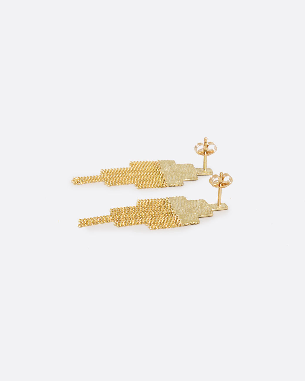 laying down view of two gold earrings that are in the shape of squares that have been stacked in a pyramid like shape. the top half of the earring is solid, and the bottom half is made of chain that moves with the wearer. the post back with butterfly backings is visible. 
