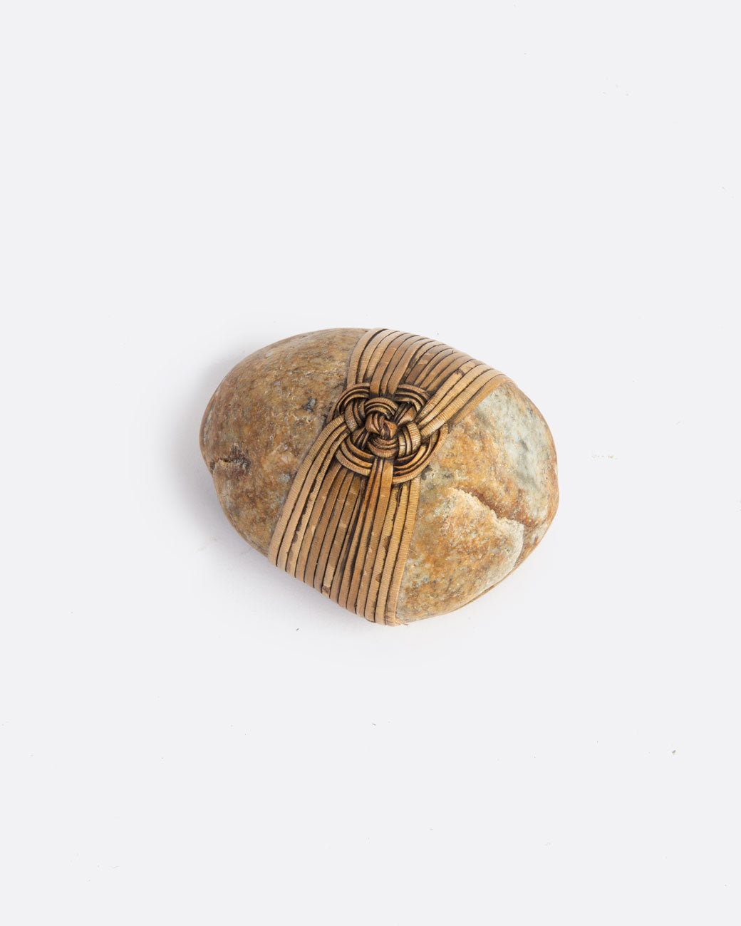 birds eye view image of a blessing stone, wrapped in a woven grass. 