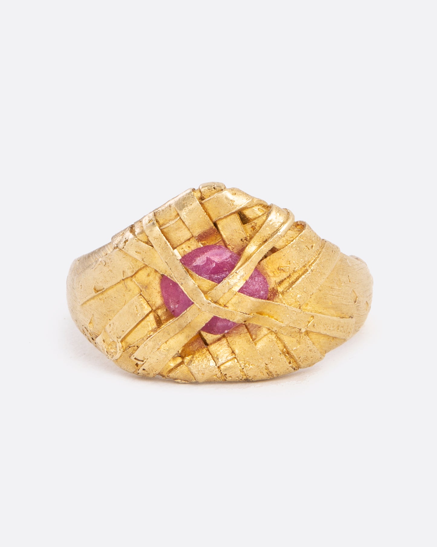 front view of a yellow gold ring with a ruby wrapped in yellow gold on a flat signet band.