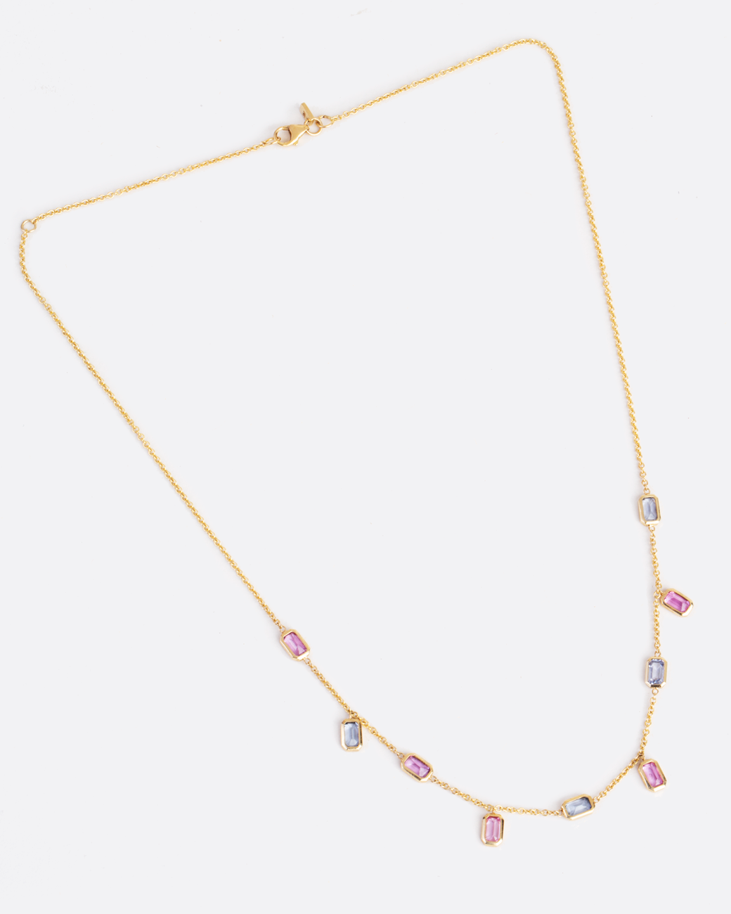 gold chain with 9 emerald cut sapphires set horizontally and vertically along the chain