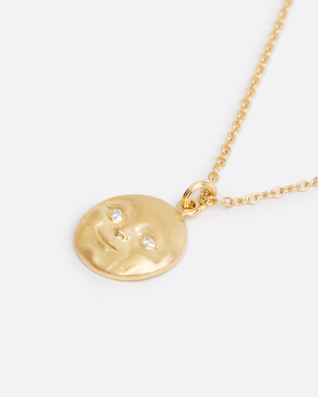 A highly detailed moonface, with little diamonds eyes hangs from a sturdy chain