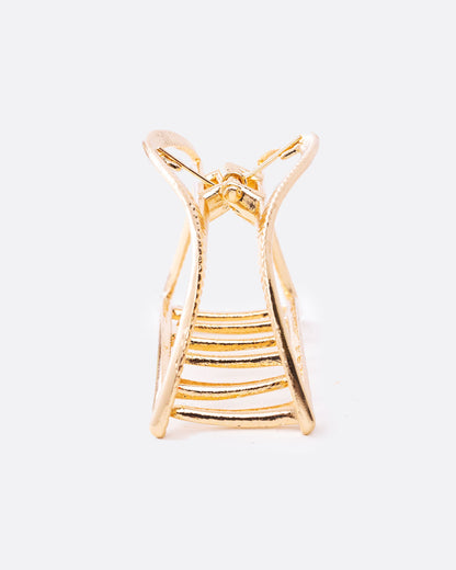 A gold hair clip with a spring loaded top and teeth at the base. Shown from the front.