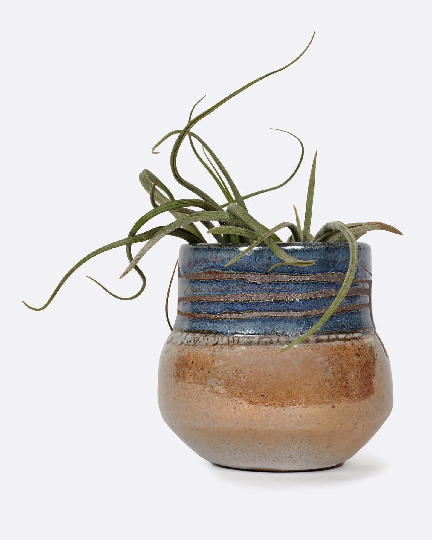 A short, round vase that's glazed half blue and half brown.