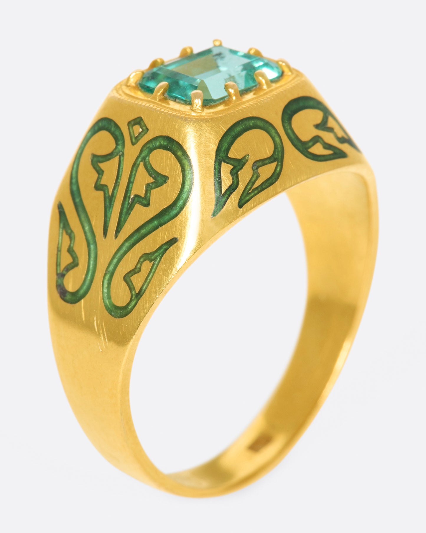 A gold ring featuring a bright Colombian emerald at its center and matching enamel details.