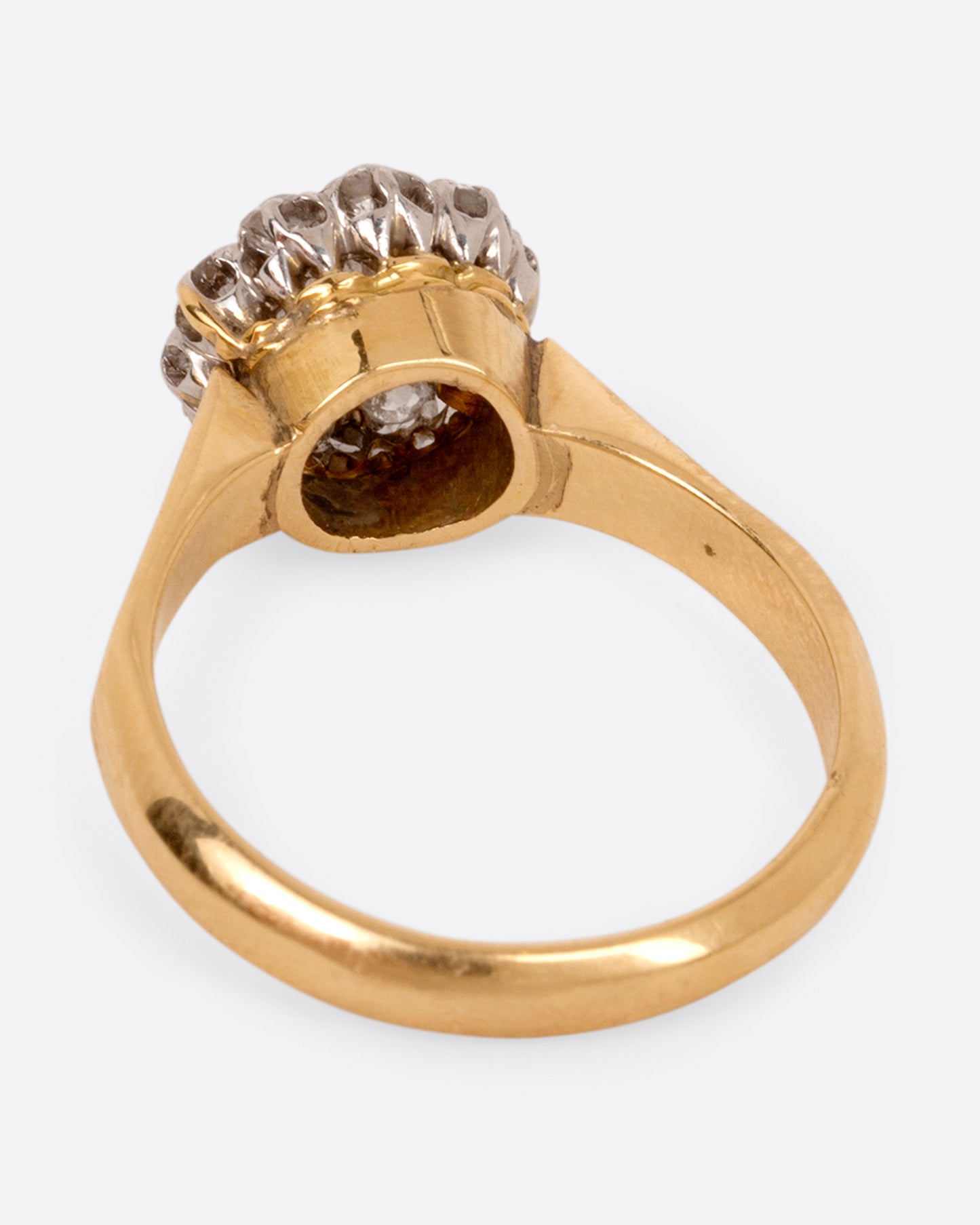 A wide flat yellow gold ring with a flower-shaped cluster of diamonds, shown from the back.