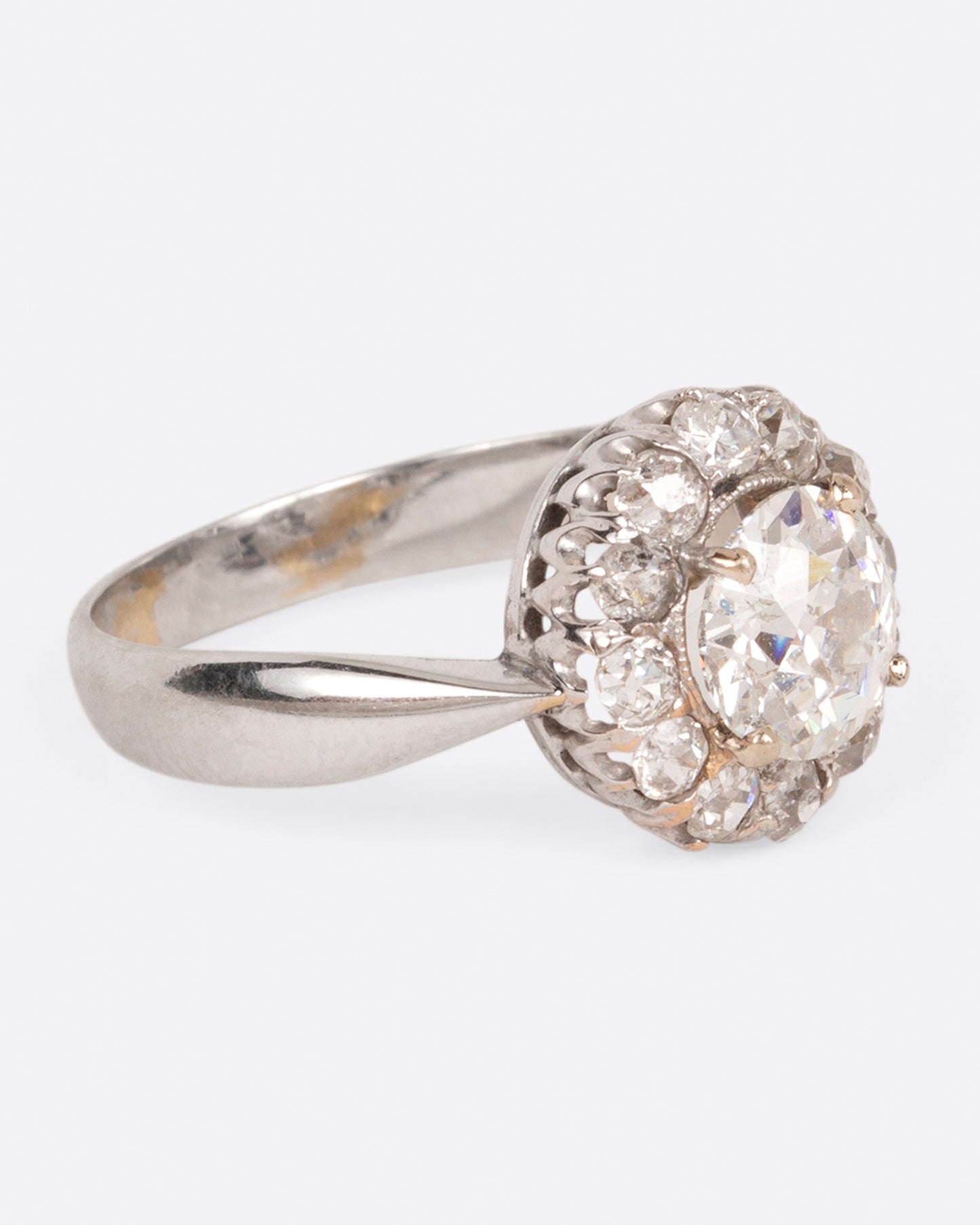 A white gold ring with a tapered band and a flower-shaped cluster of diamonds, shown from the side.