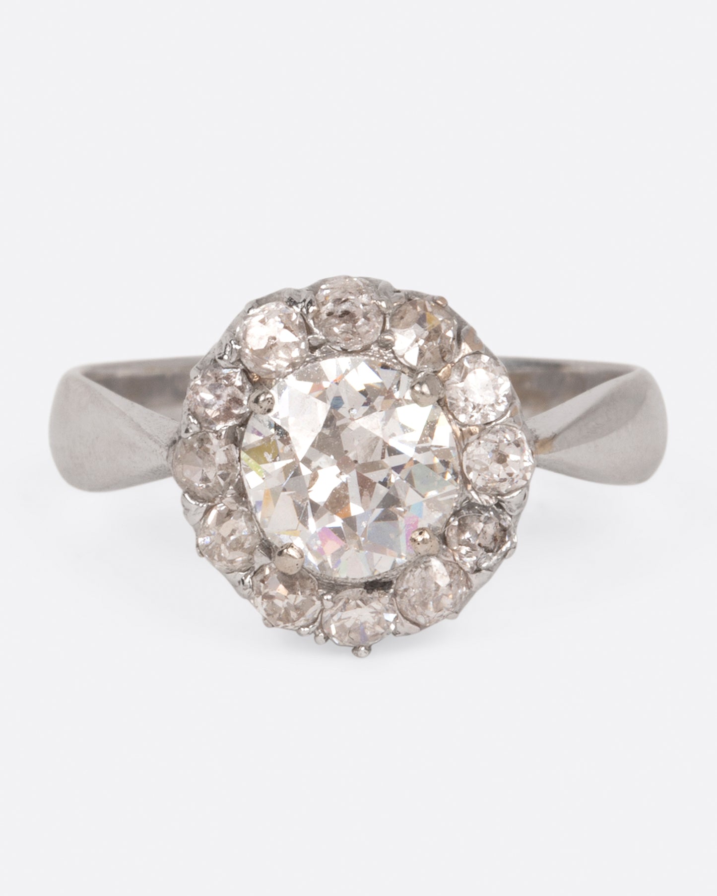 A white gold ring with a tapered band and a flower-shaped cluster of diamonds, shown from the front.