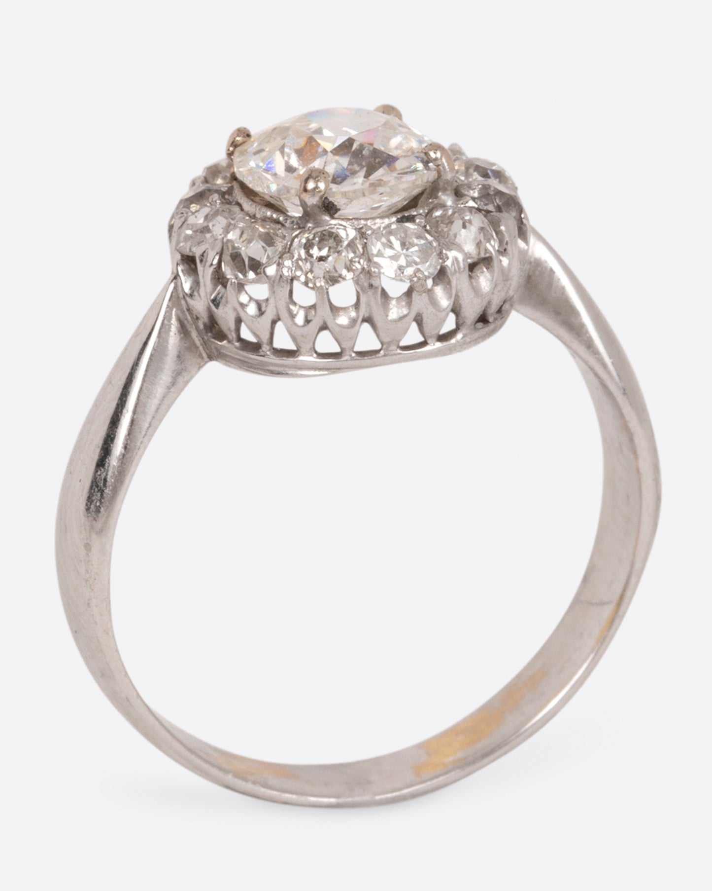 A white gold ring with a tapered band and a flower-shaped cluster of diamonds, shown standing.