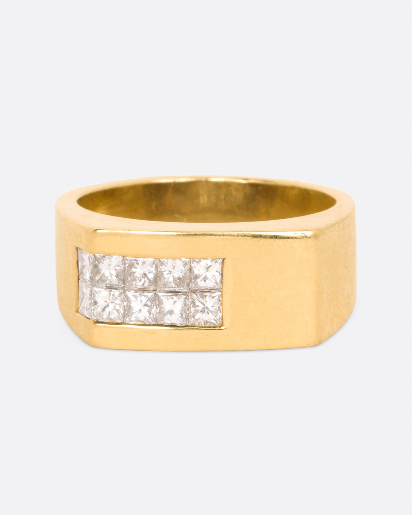A yellow gold rectangular signet ring with 10 princess cut diamonds on one corner, shown from the front.