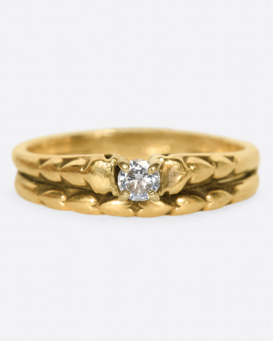 This ring gives the illusion of two; two stacked bands with heart details and a prong set diamond at their center.