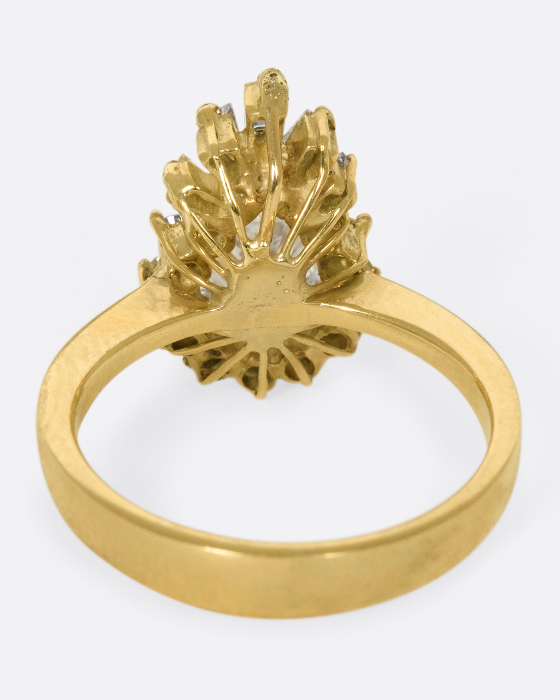 A tapered ring with a pale yellow, pear shaped diamond at its center with a round and baguette diamond halo.
