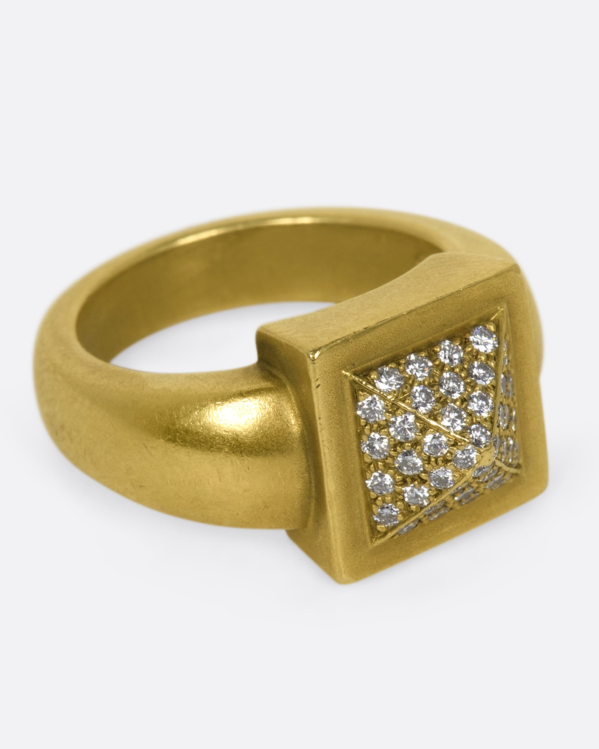 A heavy rounded gold ring with a square, pointed face covered in diamonds.