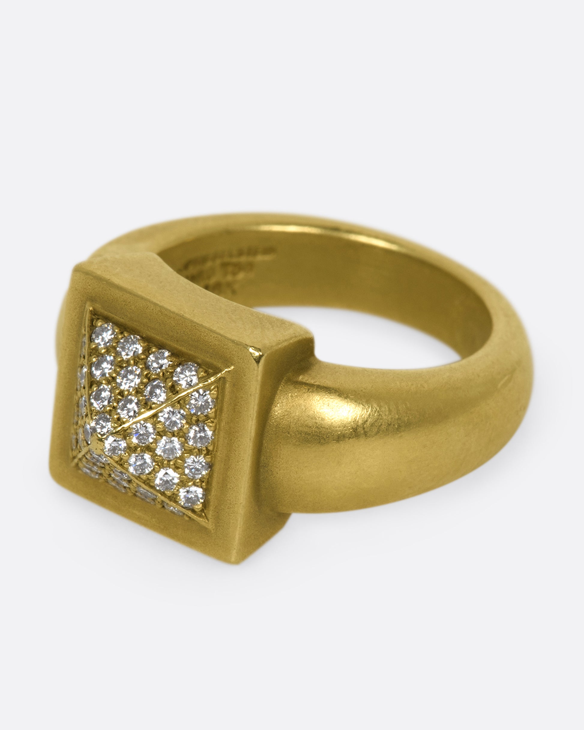 A heavy rounded gold ring with a square, pointed face covered in diamonds.