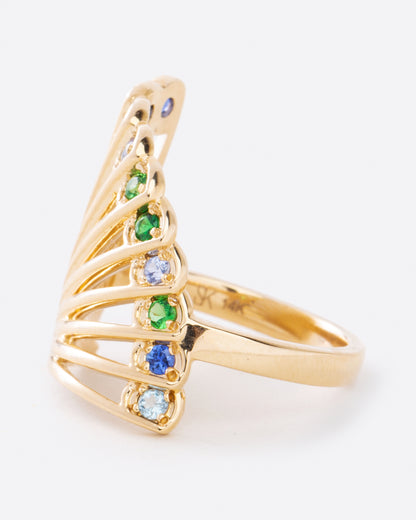 A yellow gold ring in the shape of a fan with multicolor sapphires along the top edge. Shown from the side.