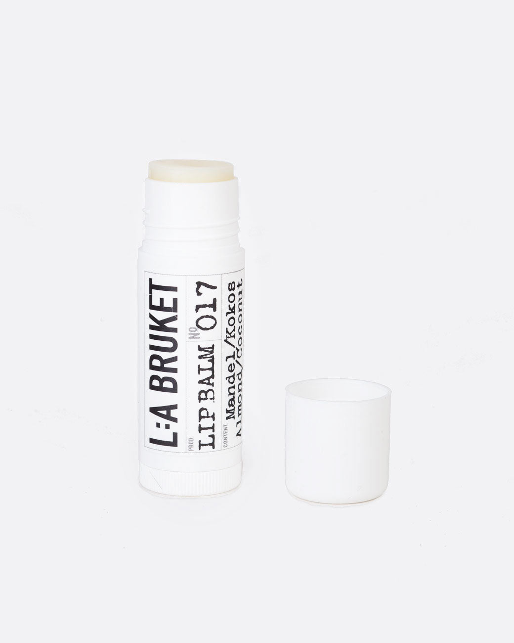 17 mL tube of L:A Bruket Almond & Coconut Lip Balm uncapped to show the clear white balm